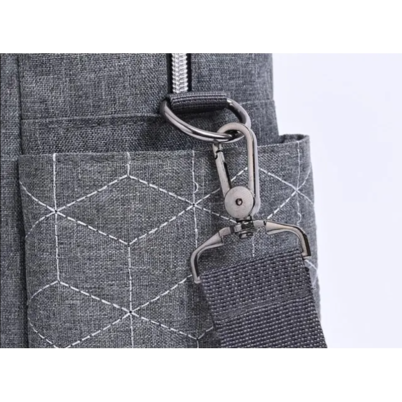 Détail du tissu matelassé en nid d’abeille du sac à langer gris et de l'attache solide en métal de la bandouillère