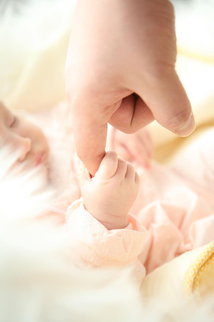 Bébé qui tient le doigt de maman